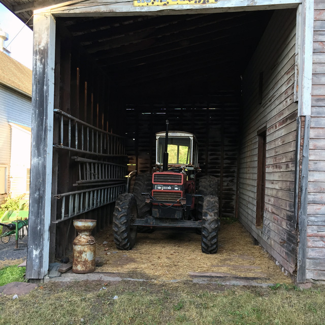 An old tractor with a rusted milk can and strainer.